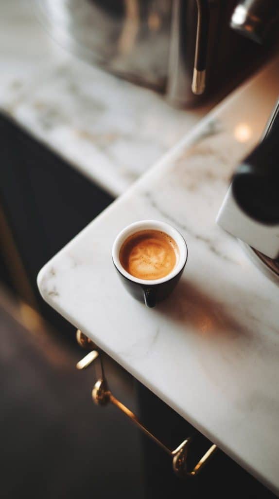 a freshly brewed espresso shot in a small white cup, the rich crema sitting on top.